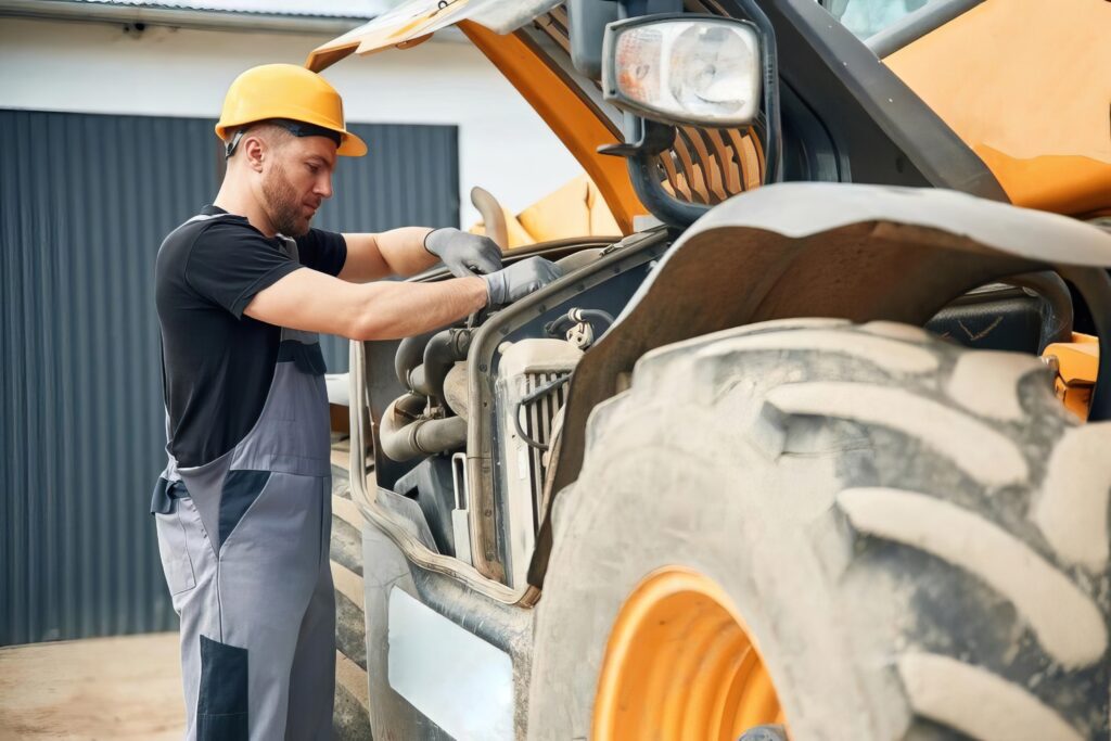 man reaparing broken construction equipment